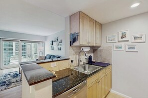 A modern kitchen with a granite countertop, stainless steel sink, and wooden cabinets. - Newmark condo near attractions with heated pool, hot tub, & fitness room (Seattle)