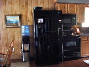 Una cocina con armarios de madera, un refrigerador, un microondas y una estufa.