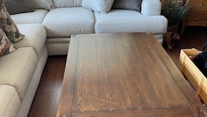 Una sala de estar con una mesa de centro de madera, un sofá gris y un aparador de madera.