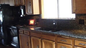 Una cocina con armarios de madera, encimera de granito, pileta de acero inoxidable y horno empotrado.