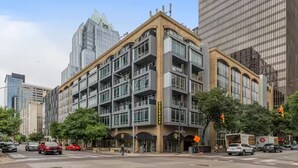 Ein mehrstöckiges Gebäude im modernen Architekturstil mit einem markanten Eingang im Winkel und großen Fenstern.