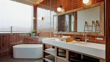 A modern bathroom with a freestanding bathtub, a large mirror, and a vanity with a sink.