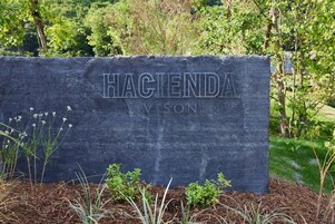 Un letrero de piedra con el nombre 'Hacienda Vison' en un área ajardinada con follaje.