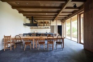 Una cocina moderna con una mesa y sillas de madera, estufa integrada y un ventanal grande.