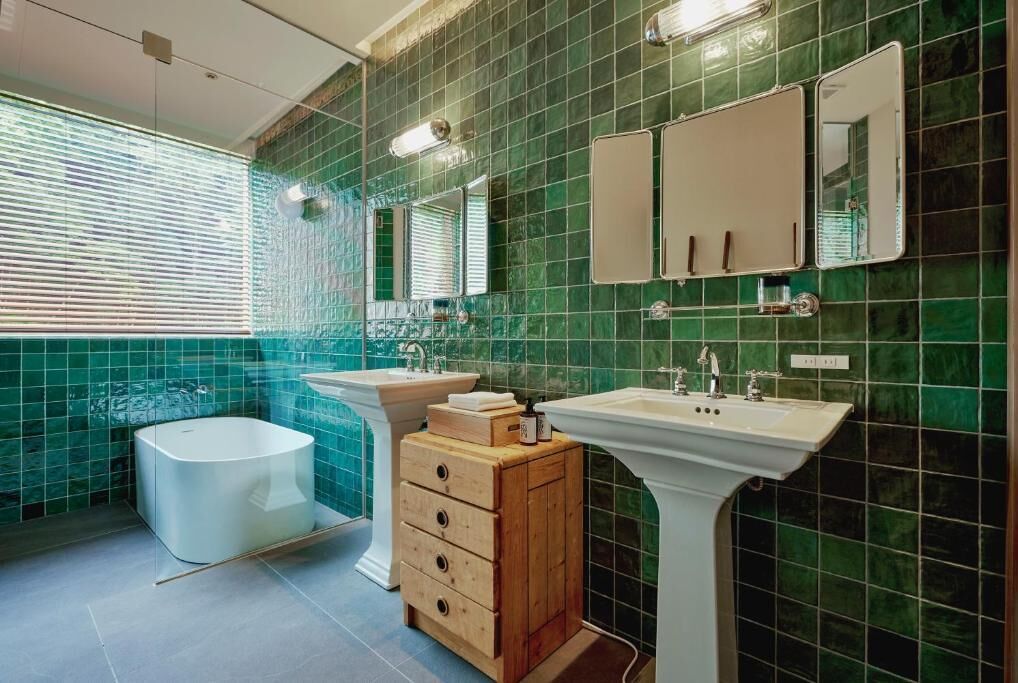 A bathroom with a bathtub, two sinks, a vanity with drawers, and a mirror.