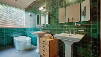 A bathroom with a bathtub, two sinks, a vanity with drawers, and a mirror.