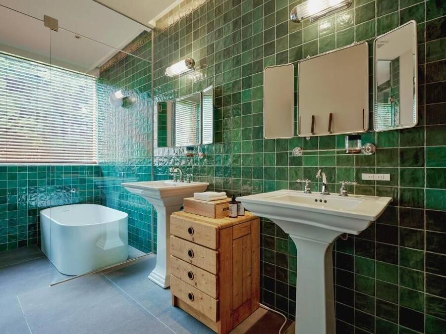 A bathroom with a bathtub, two sinks, a vanity with drawers, and a mirror.