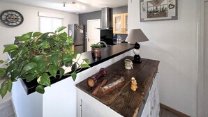 A kitchen with a wooden countertop, a potted plant, a lamp, and a decorative clock. - Maison de charme conviviale (Montgivray)