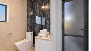 Et badeværelse med toilet, håndvask og spejl.