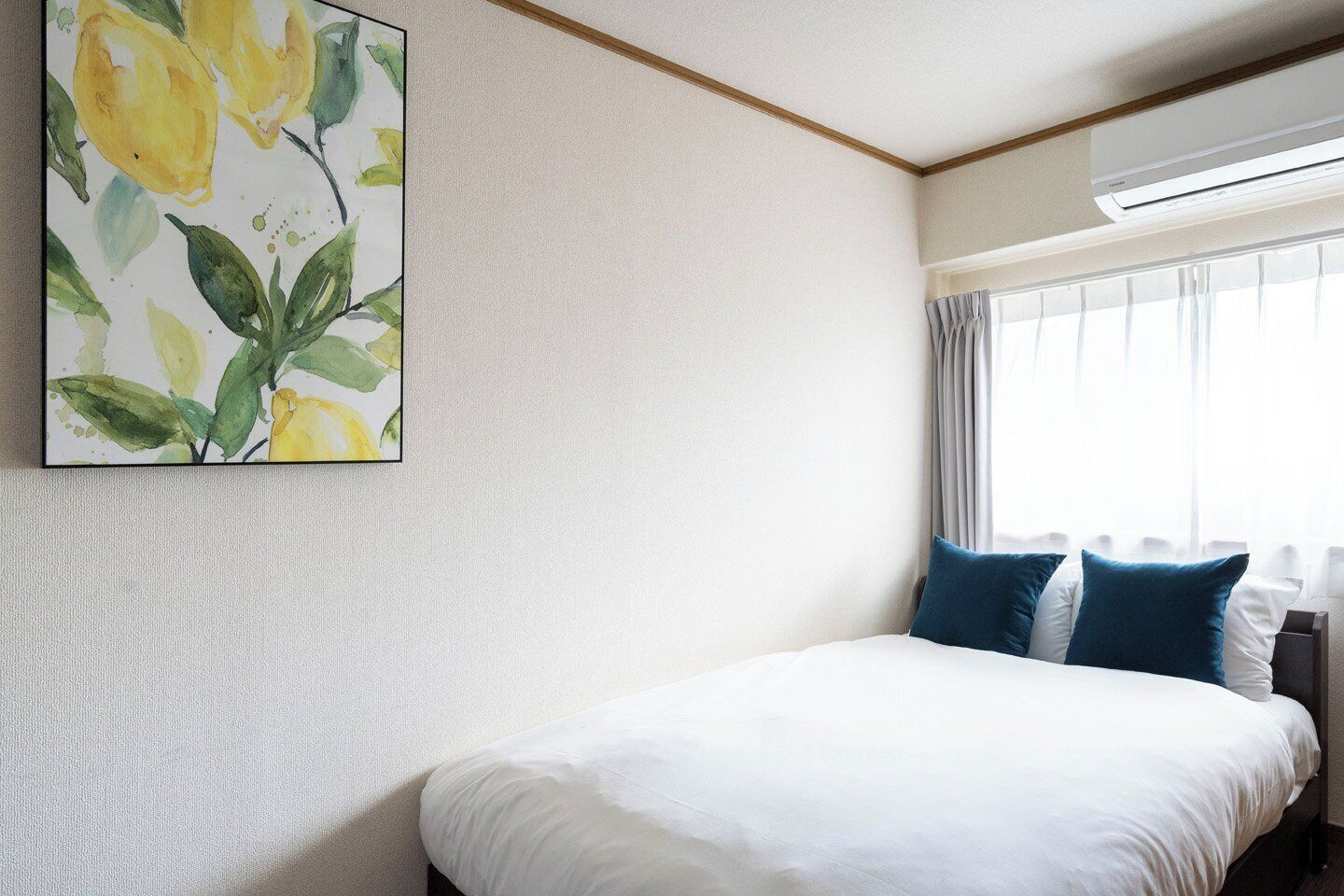 Ein Hotelzimmer mit Bett, einem Blumenbild, einem Fenster mit Vorhängen und einer Klimaanlage.