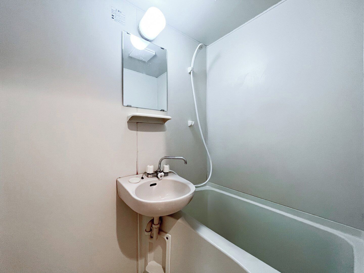 A bathroom with a sink, mirror, and shower.