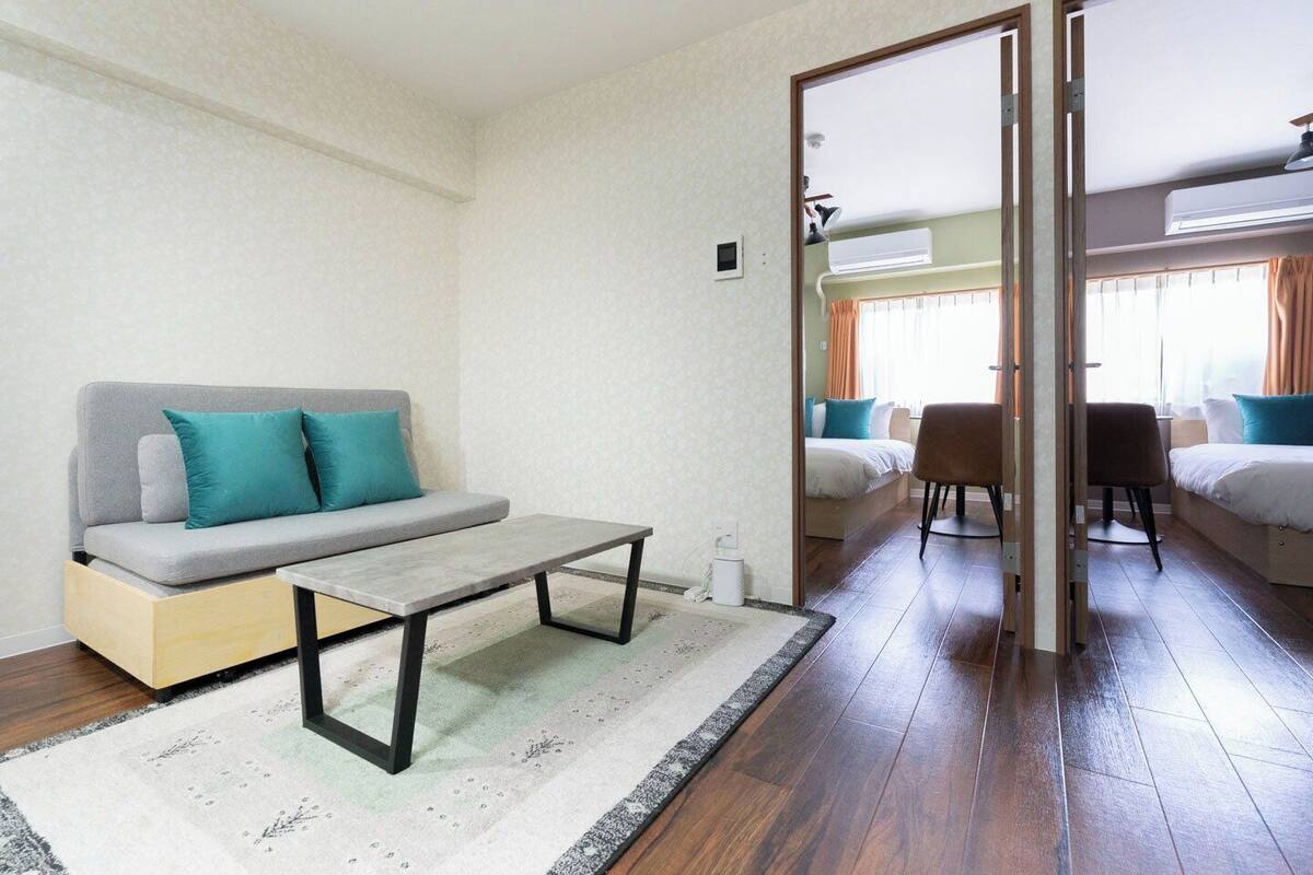 A modern living room with a sofa, a coffee table, and a dining area with chairs.