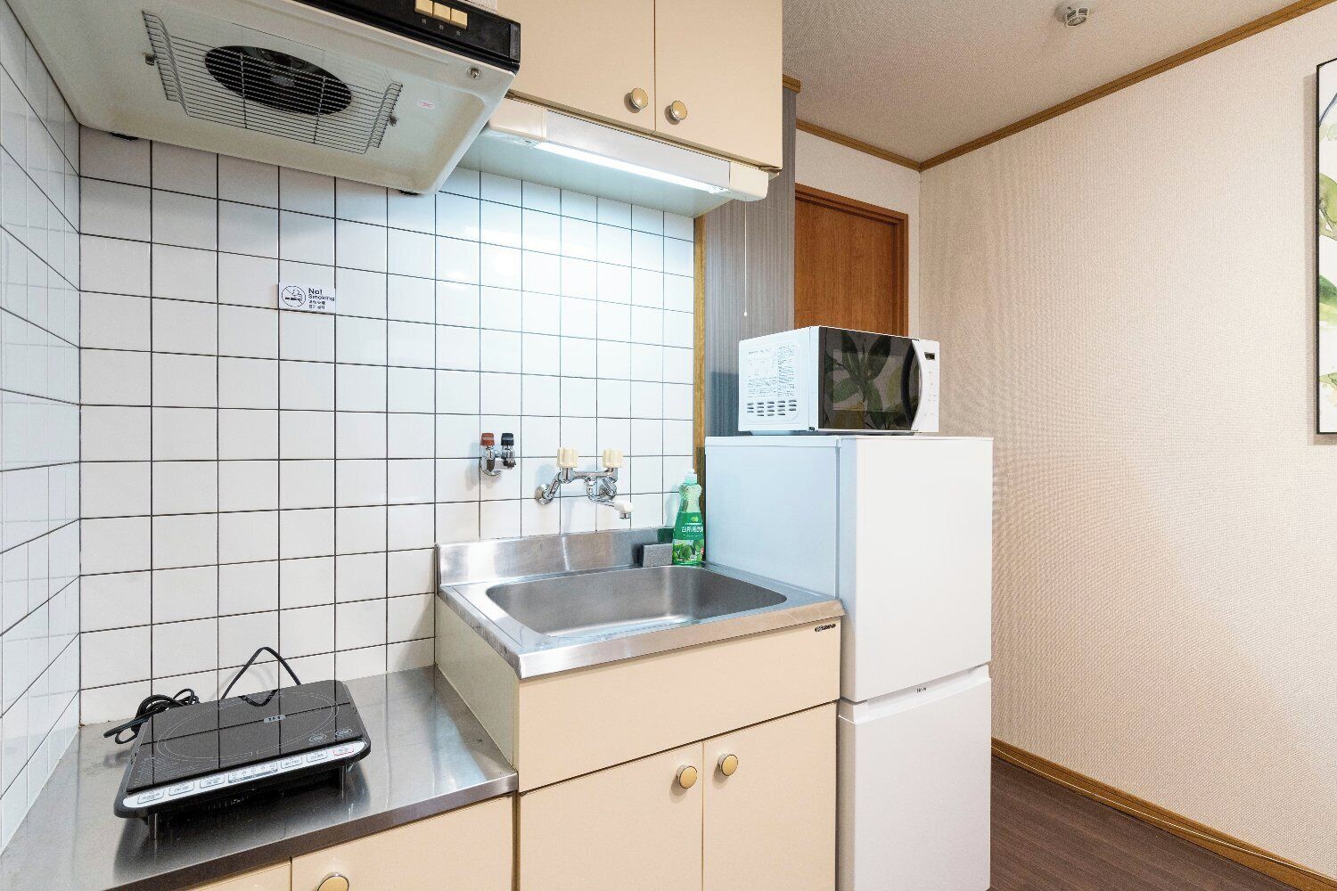 A compact kitchen with a microwave, sink, and stove top.