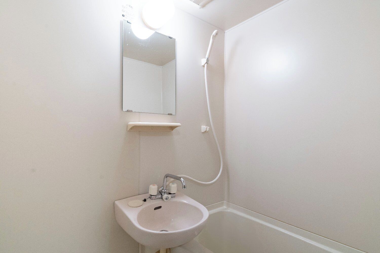 Een badkamer met een wastafel, spiegel en douche.