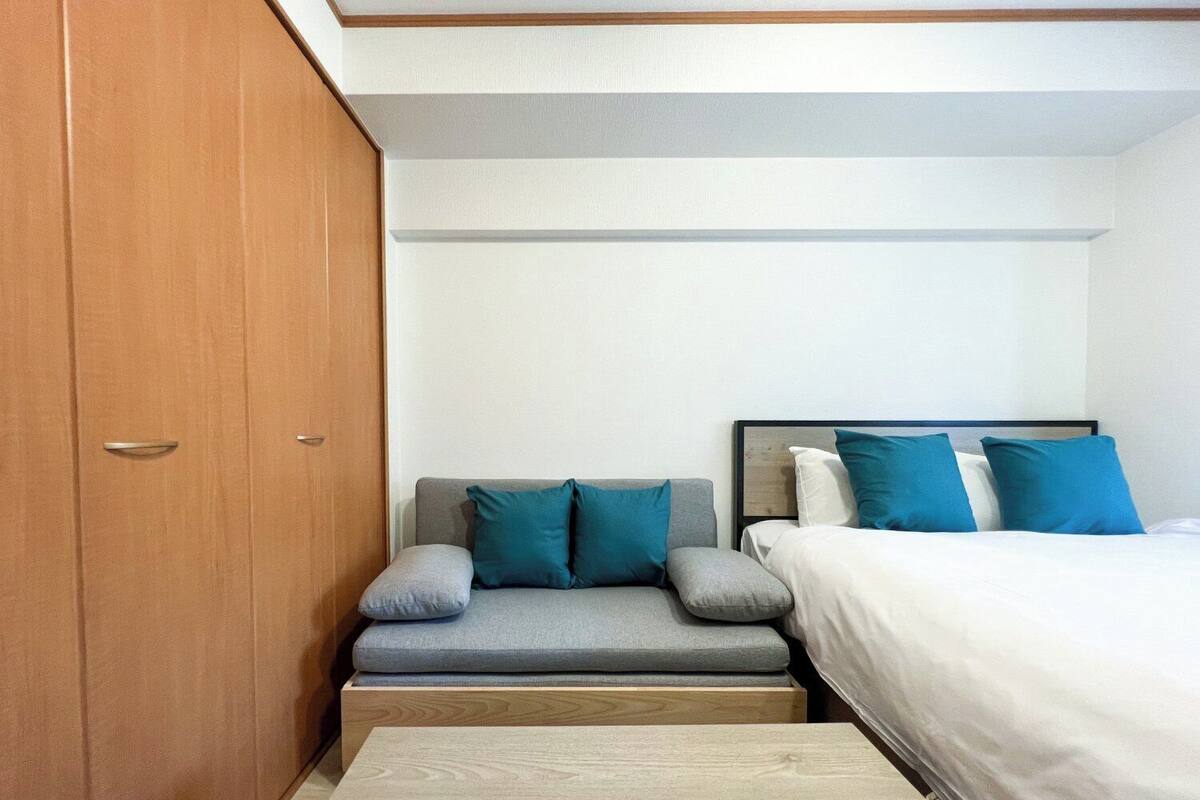 A bedroom with a sofa, a bed, and a wardrobe.