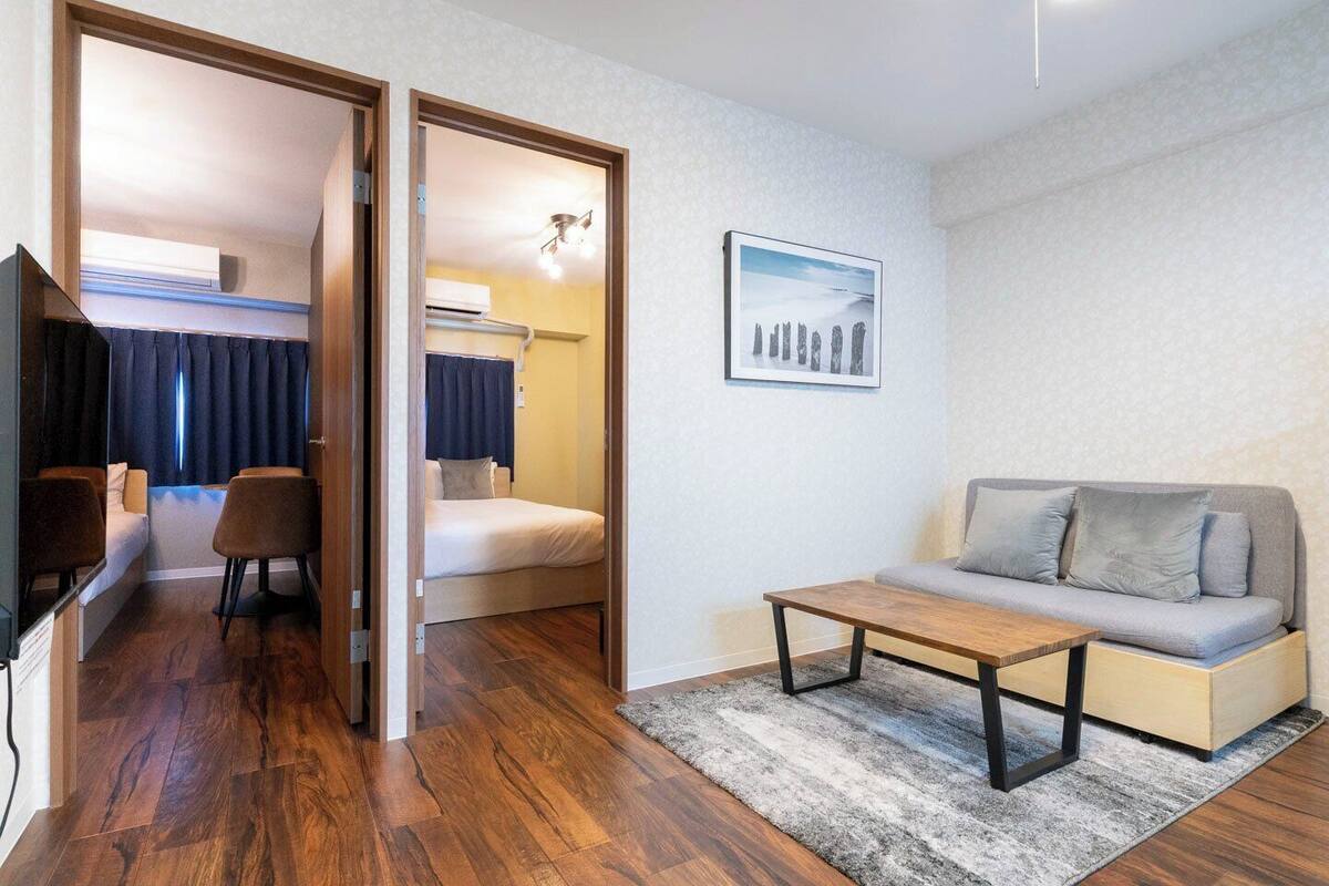 A compact room with a bed, a sofa, a coffee table, and a TV.