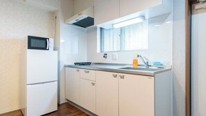 A compact kitchen with a microwave, sink, and wooden flooring. - Alita Mansion Kyobashi (Osaka)