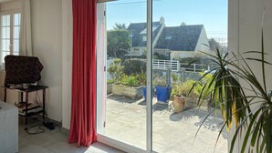 A room with a sliding glass door leading to a balcony with potted plants and a view of houses. - Beautiful home in Barneville-Carteret with WiFi (Barneville-Carteret)