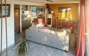 Ein Wohnzimmer mit Sofa, eine Essecke mit Tisch und eine Küche mit Schränken und Geräten.