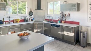 A modern kitchen with stainless steel appliances, a bowl of fruit on the counter, and a window providing natural light. - Beautiful home in Barneville-Carteret with WiFi (Barneville-Carteret)