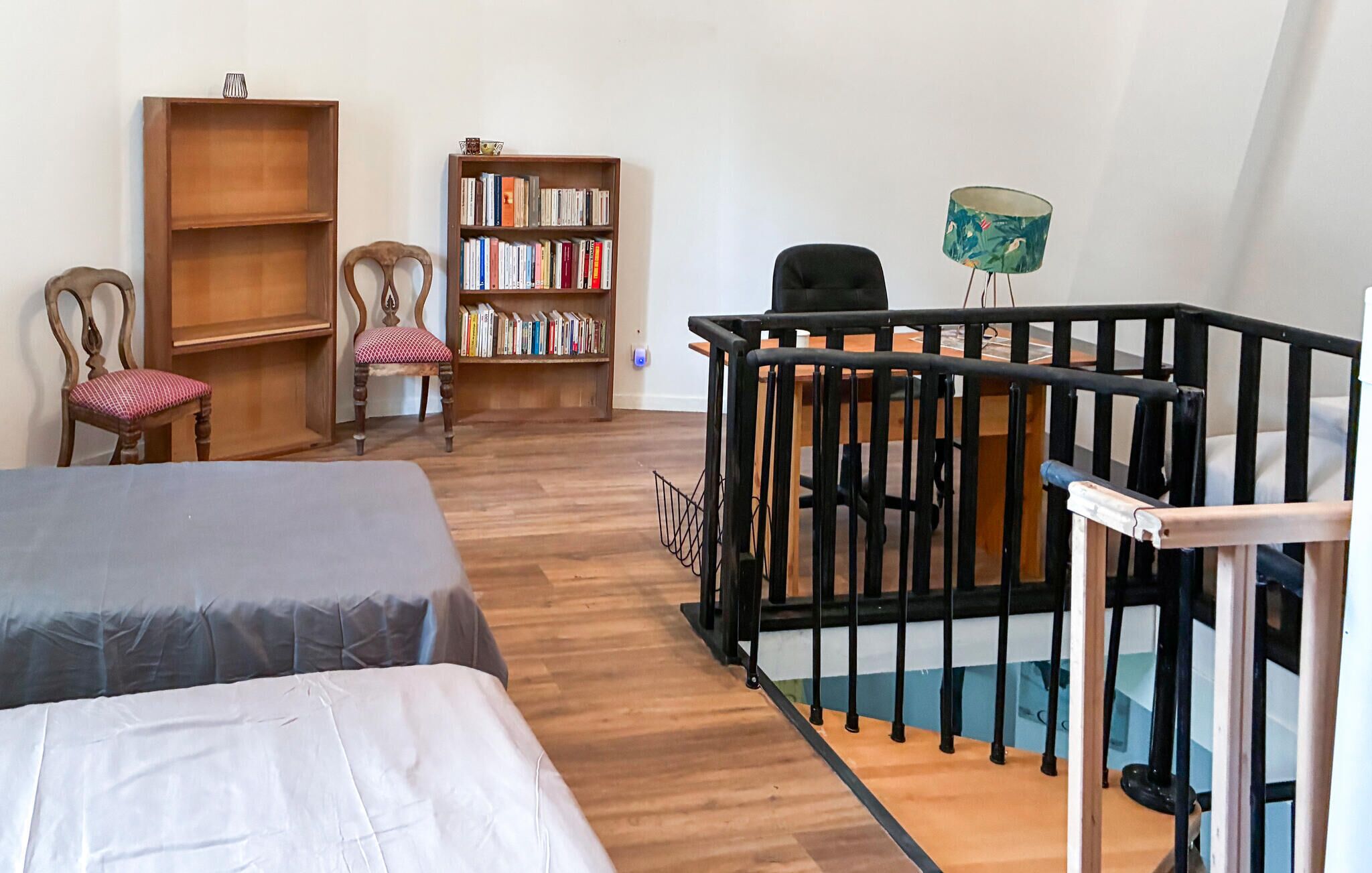 Une chambre avec deux lits, une bibliothèque, une chaise et une petite table.