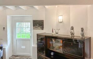 Une pièce avec une porte blanche, une fenêtre donnant sur un paysage agréable, un meuble en bois foncé doté de portes en verre et un luminaire fixé au mur.