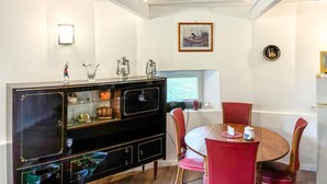 Un comedor con un aparador negro, sillas rojas, una mesa redonda y un ventanal con vistas.