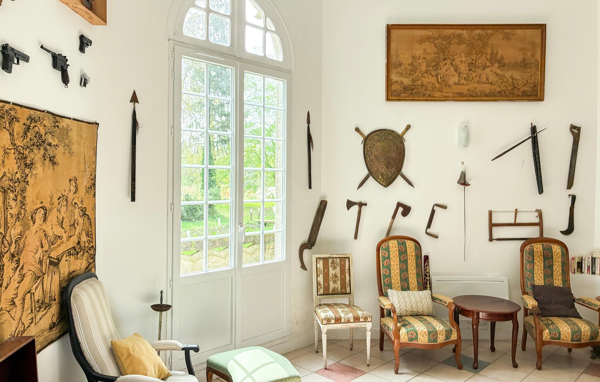 Ein Zimmer mit einem großen Fenster, einem Gemälde und verschiedenen historischen Artefakten an den Wänden.