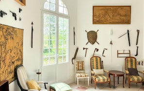 Ein Zimmer mit einem großen Fenster, einem Gemälde und verschiedenen historischen Artefakten an den Wänden.