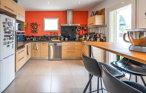 A modern kitchen with wooden cabinets, a stainless steel dishwasher, and a window above the sink. - Maison avec piscine privée (Saumane-de-Vaucluse)