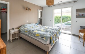 A bedroom with a bed, a bedside table, a wardrobe, a window, and a door. - Maison avec piscine privée (Saumane-de-Vaucluse)