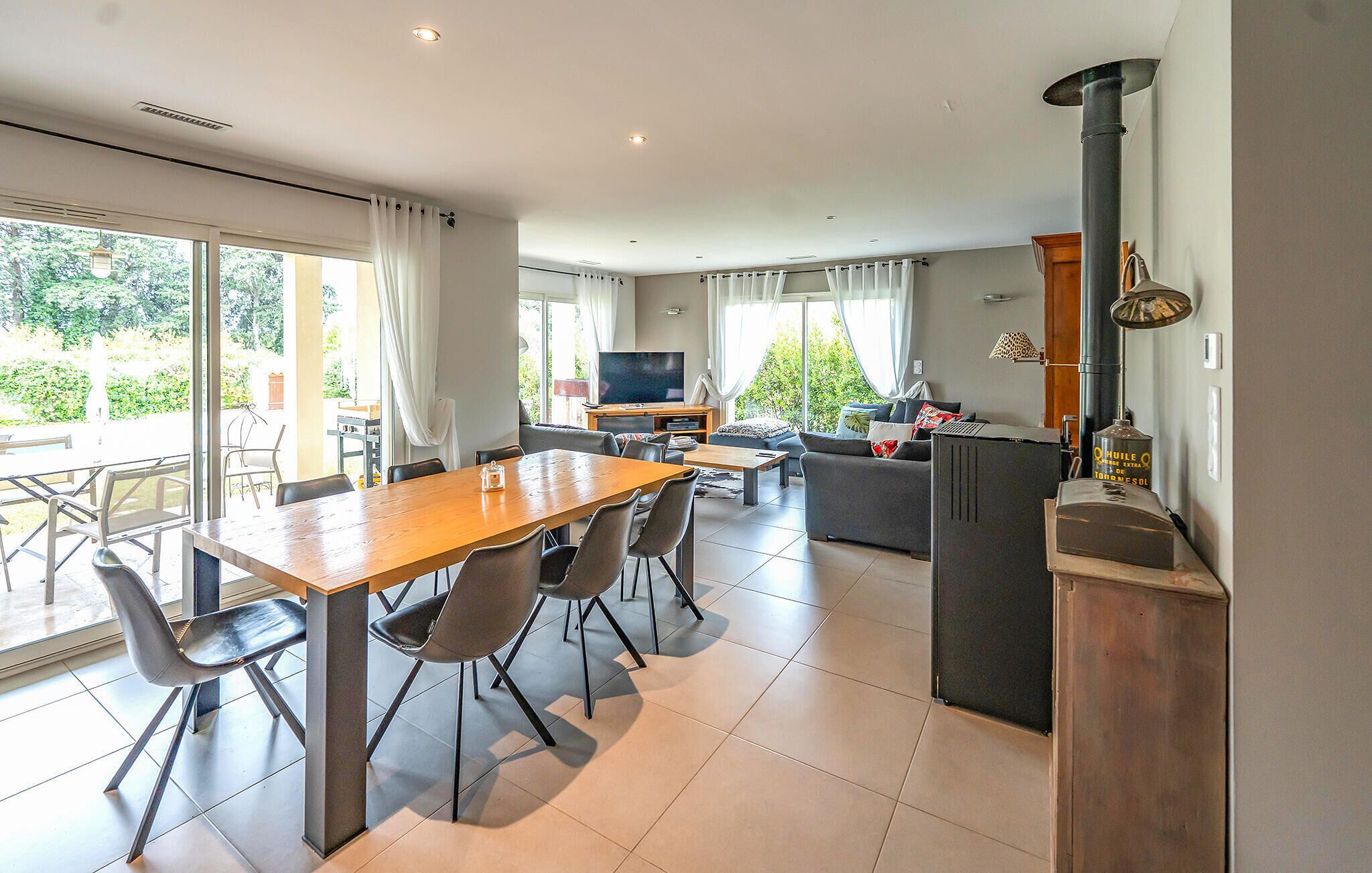 A modern kitchen with a stove, dining area with chairs, and a TV.