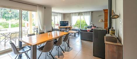 A modern kitchen with a stove, dining area with chairs, and a TV.