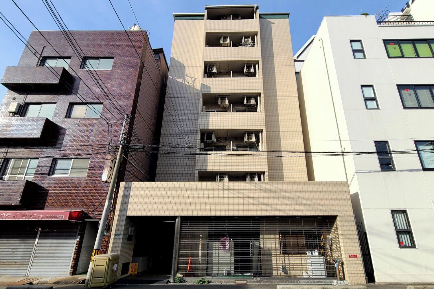 A multi-story building with a ground-level commercial space, multiple balconies, and a brick facade.