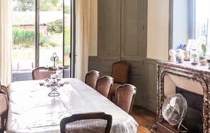 Ein Esszimmer mit gedecktem Tisch für sechs Personen, einem Kamin und Blick ins Freie.
