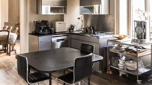 Ett modernt kök med vitvaror i rostfritt stål, ett matbord med stolar och en diskmaskin.