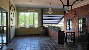 A spacious indoor area with a tiled floor, large windows, and a brick wall. - Peya Rama-7 (Bang Kruai)