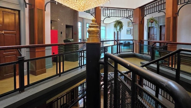 A multi-level hotel lobby with a grand chandelier, wooden railings, and a staircase. - Peya Rama-7 (Bang Kruai)
