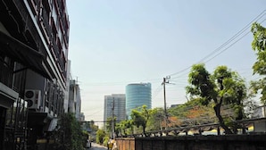A street with buildings, a water tank, and trees. - Peya Rama-7 (Bang Kruai)