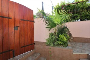 A wooden gate, a small garden with plants, and a tiled area. - Apartment Ticak (Klimno)