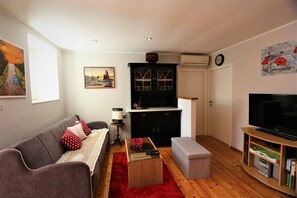 A living room with a sofa, a coffee table, a TV, a cabinet, and artwork on the walls.