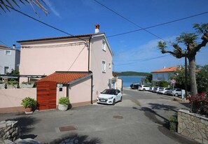 A residential street with a parked white car, a red-roofed building, and a clear blue sky.