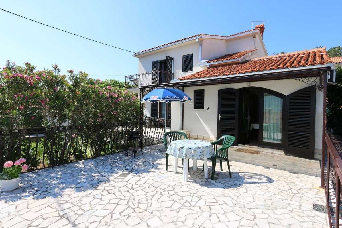 A building with a tiled roof, a balcony, and a patio area with a table and chairs.