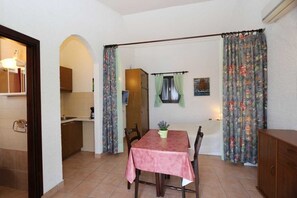 Ein Essbereich mit Tisch, Stühlen, einer Topfpflanze und einer Küche im Hintergrund.