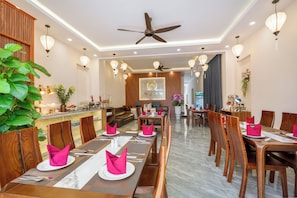 Comedor de hotel con mesas y sillas de madera, y una barra.
