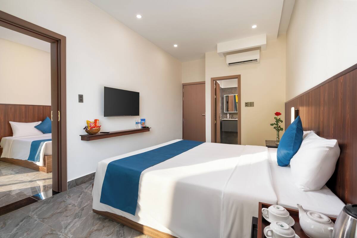 A hotel room with a large bed, a television, a small table with tea sets, and a mirror on the wall.