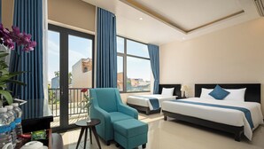 A hotel room with a large bed, a sofa, a small table, and a balcony with curtains. - Corner Centre Villa Hoi An (Da Nang)
