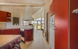 A modern kitchen with a central island, a built-in oven, and a large window. - Lovely home in Otterup with sauna (Otterup)