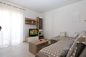 A modern living room with a sofa, a coffee table, a TV, and a wooden cabinet. - Apartment Samsa (Čižići - island Krk)