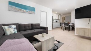 Uma sala de estar moderna com um sofá, mesa de centro e uma pintura de uma praia.